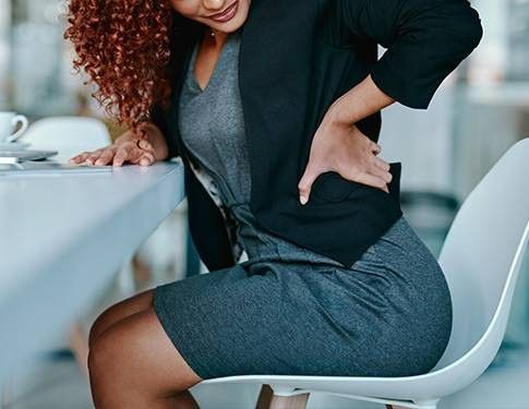 donna seduta su una sedia che si tocca la schiena