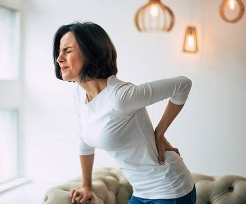 donna di mezza età che si tocca la schiena dolorante