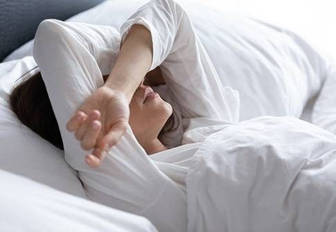 donna a letto che si copre il volto