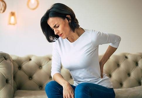 donna sul divano con schiena dolorante