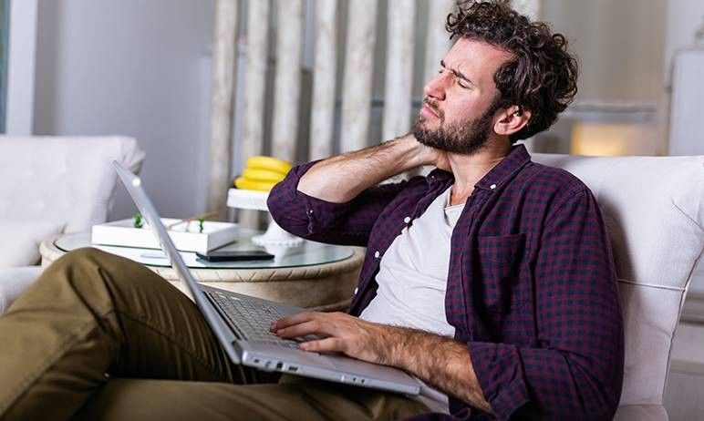 ragazzo al pc che si tocca la cervicale