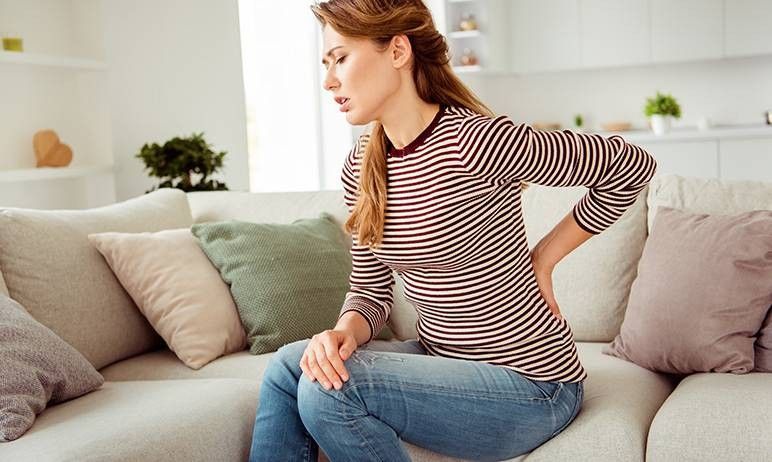 ragazza che si tocca la schiena con smorfia di dolore